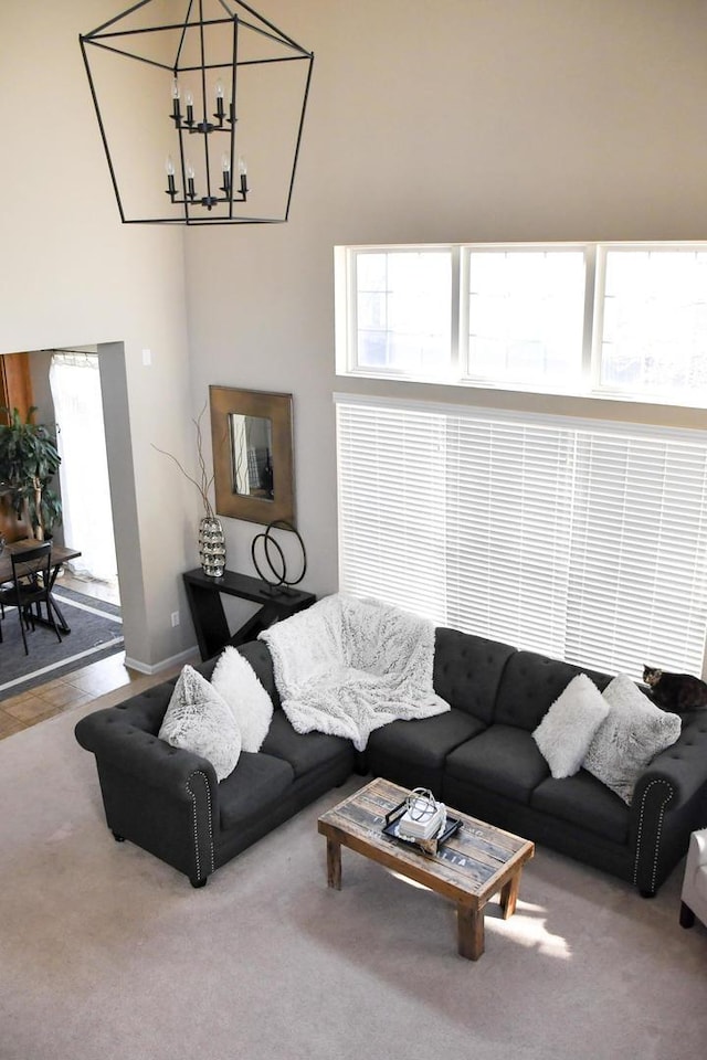 living area featuring a high ceiling, carpet flooring, baseboards, and a notable chandelier