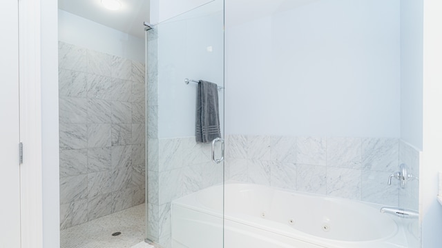 bathroom featuring a tub with jets and a tile shower
