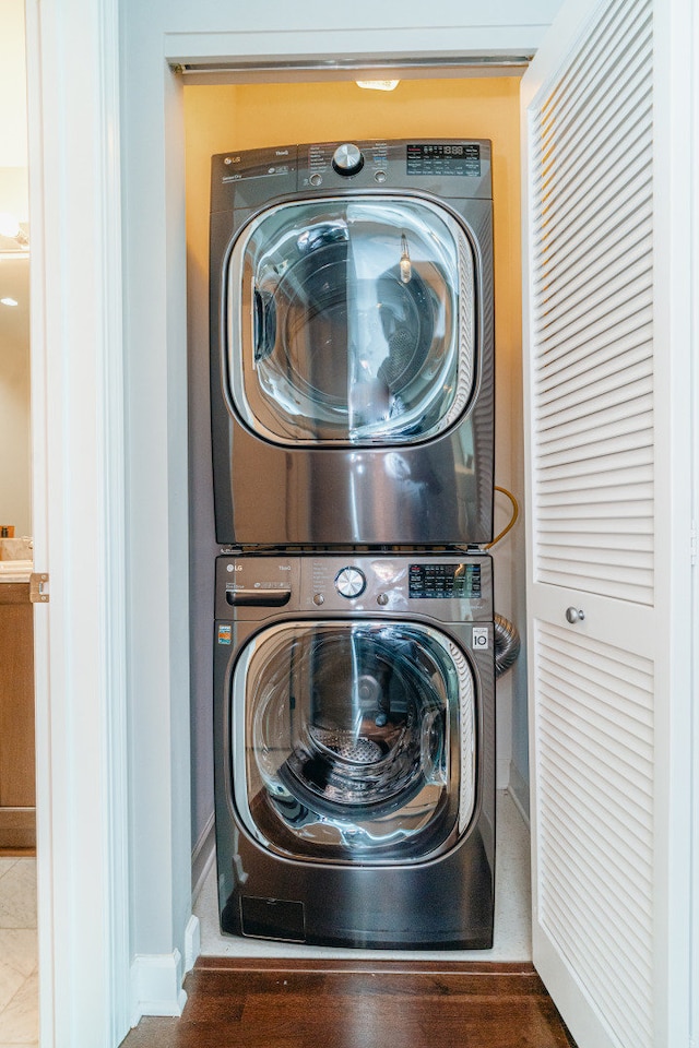 clothes washing area with stacked washer / drying machine and baseboards