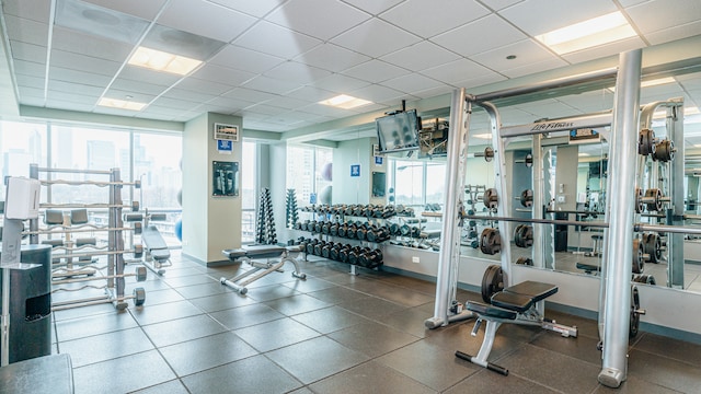 exercise room with a paneled ceiling and baseboards