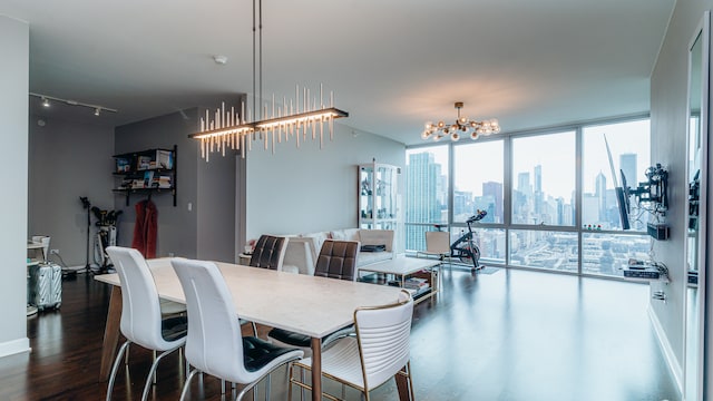 dining area with a chandelier, expansive windows, dark wood-style flooring, a view of skyline, and track lighting