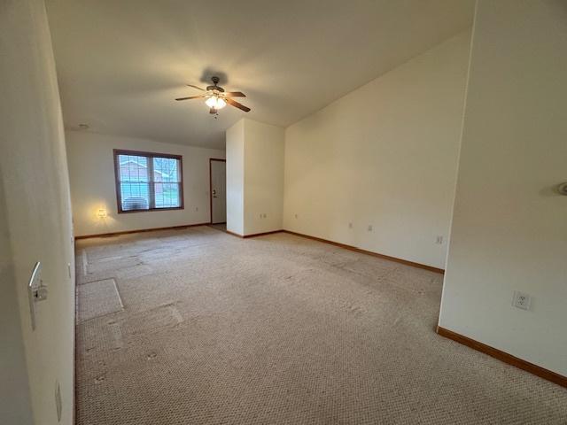 empty room featuring baseboards, ceiling fan, and light colored carpet