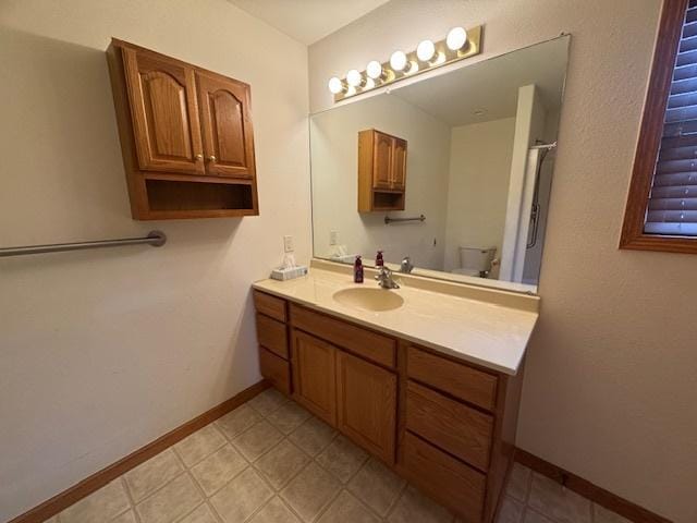bathroom with baseboards, vanity, and toilet