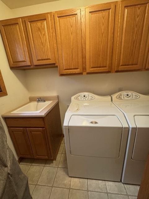 clothes washing area with washing machine and clothes dryer, a sink, light tile patterned floors, and cabinet space