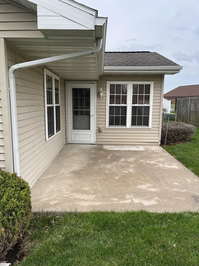 doorway to property featuring roof with shingles and a patio