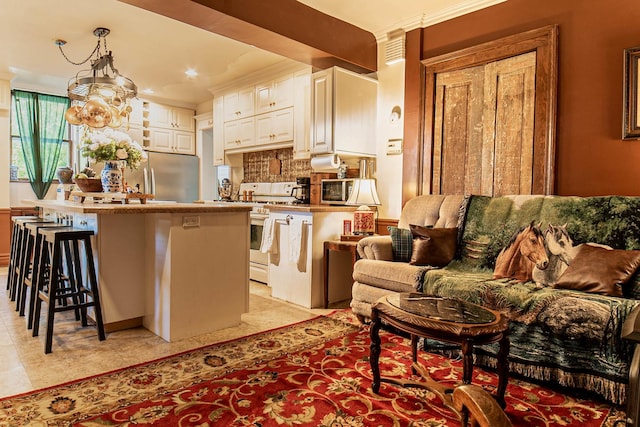 105 S High St, Galena, IL 61036 - kitchen with tasteful backsplash, a breakfast bar area, stainless steel fridge, white gas range oven, and white cabinetry