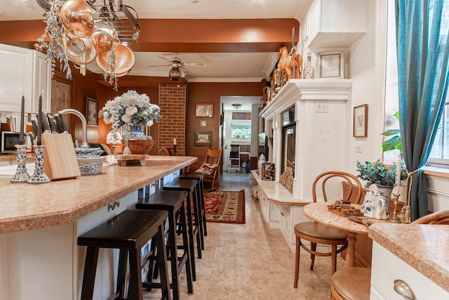 105 S High St, Galena, IL 61036 - interior space with light countertops, a breakfast bar, a ceiling fan, a fireplace, and white cabinetry