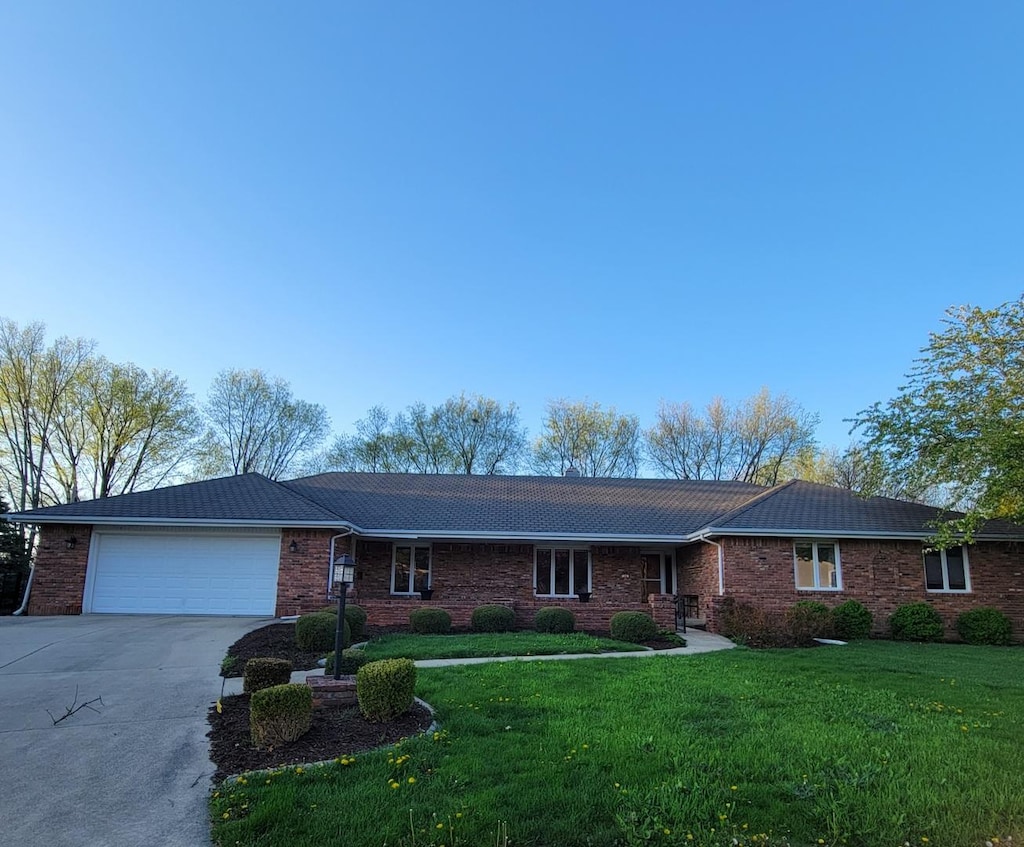 single story home featuring an attached garage, a front lawn, driveway, and brick siding