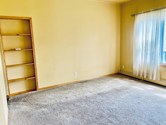 unfurnished room with carpet flooring, a baseboard heating unit, and baseboards