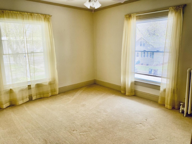 unfurnished room with ceiling fan, radiator heating unit, carpet, and plenty of natural light