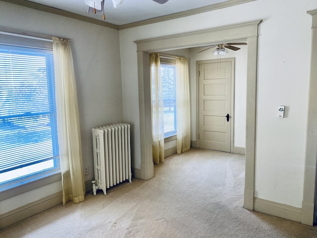 empty room with a ceiling fan, radiator heating unit, carpet, and a healthy amount of sunlight