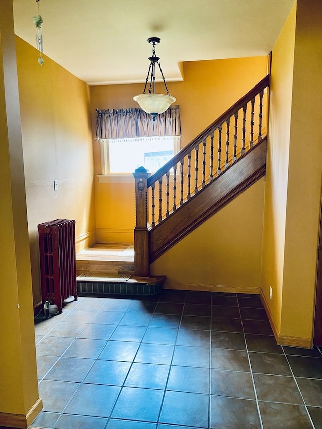 stairway with baseboards, radiator, and tile patterned flooring