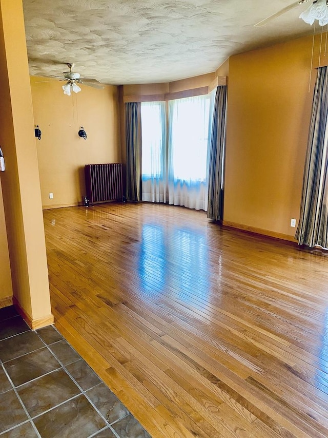 spare room with radiator, a ceiling fan, and wood-type flooring