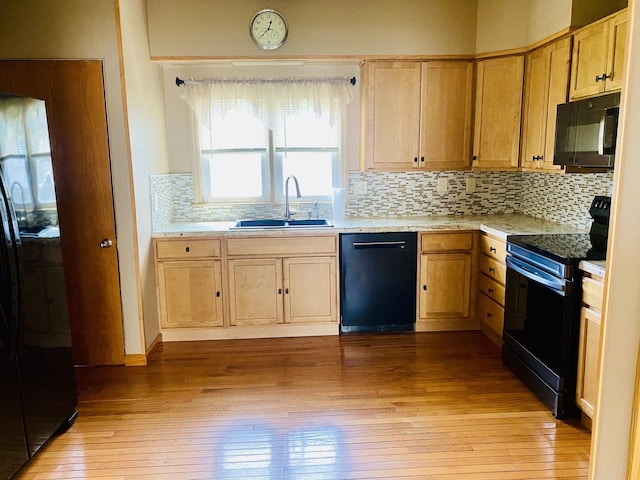 kitchen featuring decorative backsplash, a sink, black appliances, light brown cabinetry, and light wood-type flooring