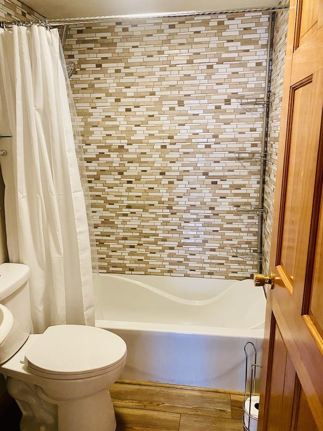 bathroom featuring wood finished floors, toilet, and shower / bath combination with curtain