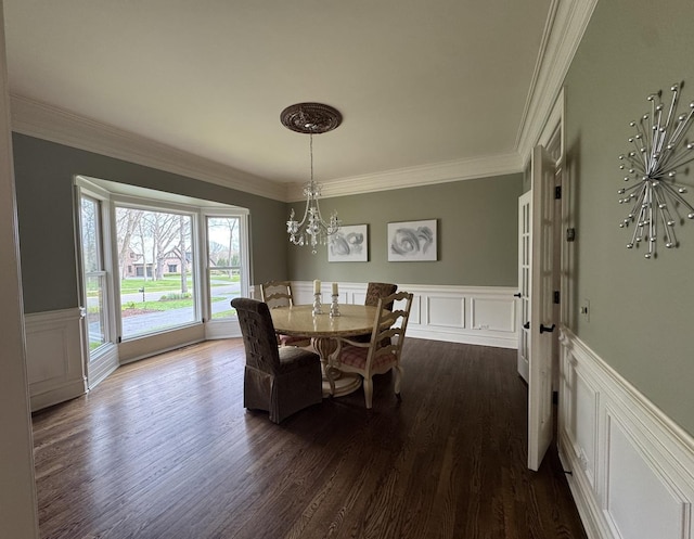 dining room featuring wainscoting, a chandelier, ornamental molding, and a decorative wall