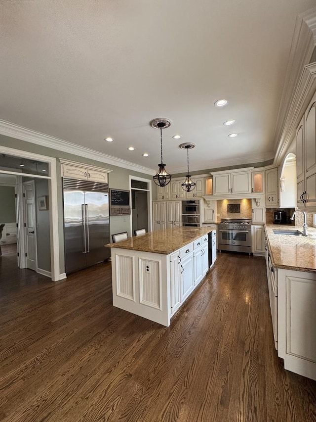 kitchen featuring crown molding, high end appliances, a center island, light stone countertops, and a sink