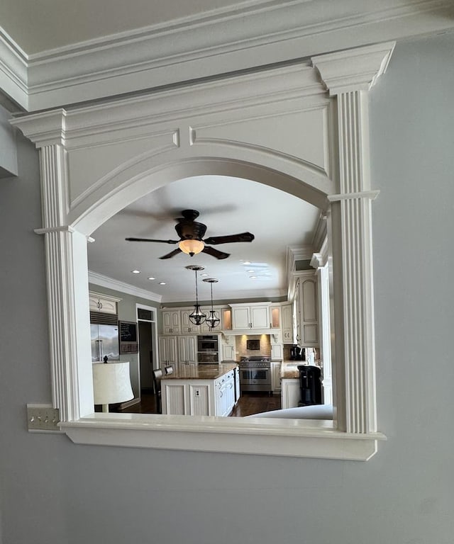 interior space with arched walkways, ceiling fan, and ornamental molding