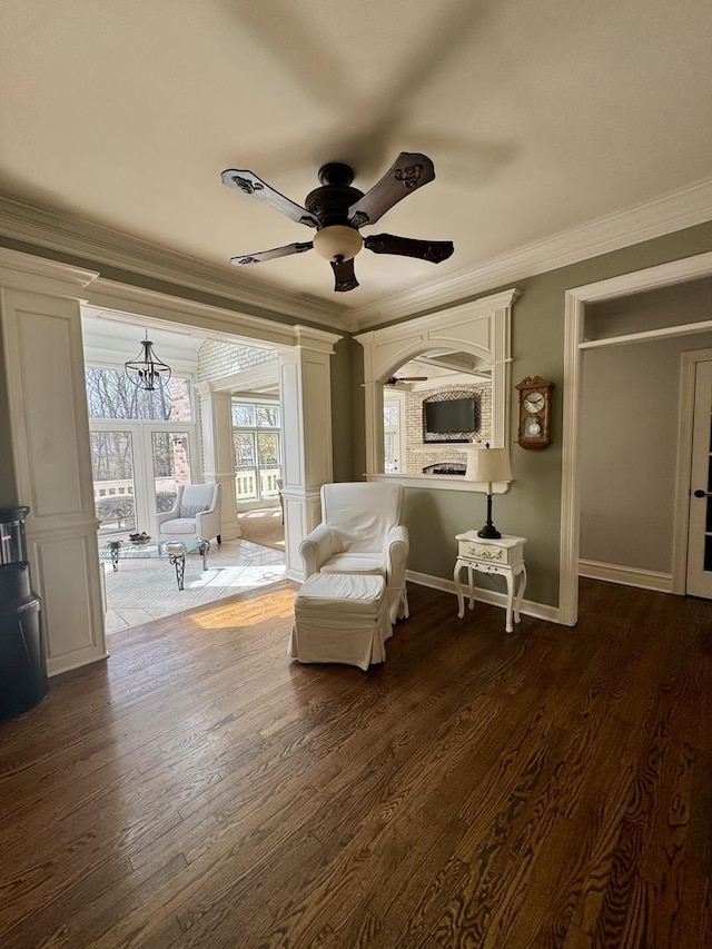 living area featuring dark wood-type flooring, ornamental molding, baseboards, and ceiling fan