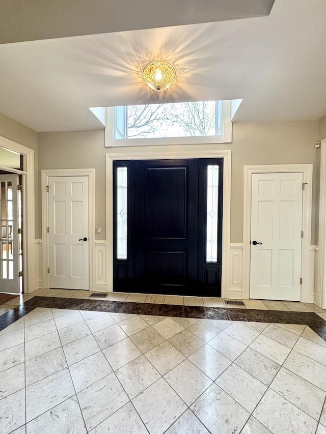 tiled entrance foyer with visible vents and wainscoting