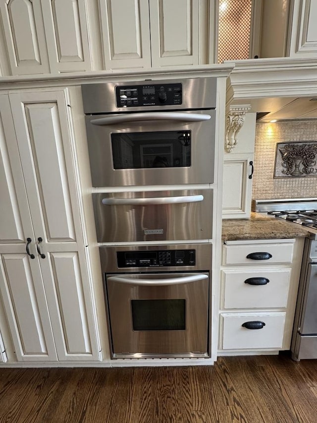kitchen featuring a warming drawer, stone countertops, backsplash, and stainless steel oven