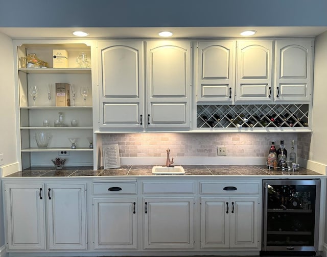 bar featuring indoor bar, tasteful backsplash, a sink, and wine cooler