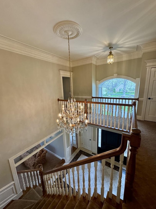stairway featuring ornamental molding, a wainscoted wall, and a chandelier