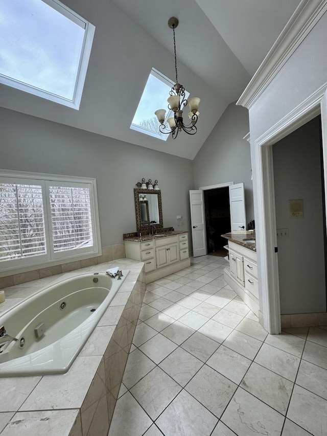 full bath with tile patterned flooring, high vaulted ceiling, two vanities, a notable chandelier, and a skylight