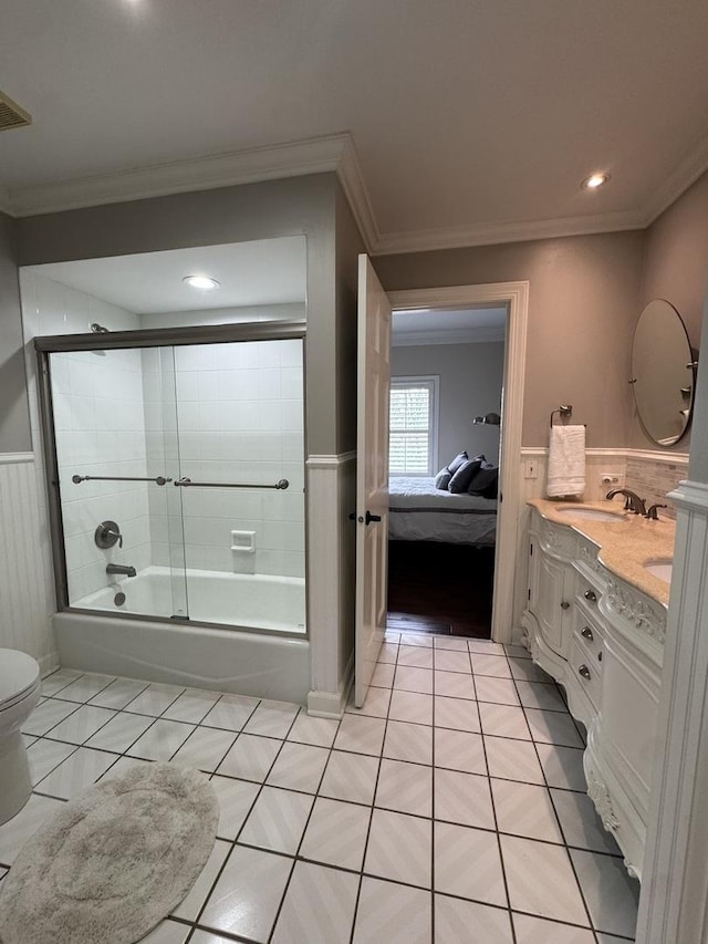 bathroom with a sink, tile patterned flooring, double vanity, enclosed tub / shower combo, and a wainscoted wall