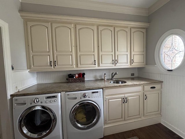 washroom featuring ornamental molding, washing machine and dryer, dark wood-style floors, a sink, and cabinet space