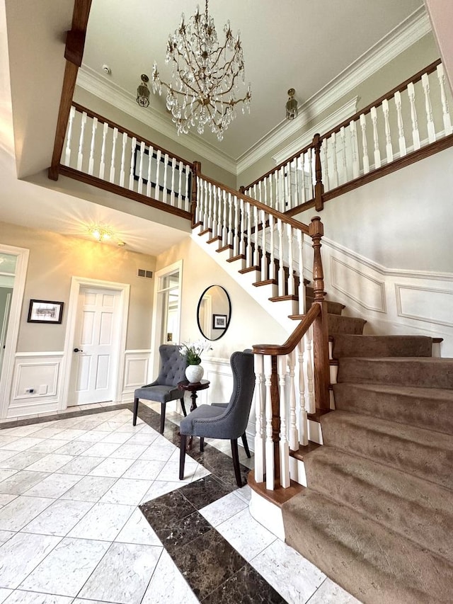 stairs with wainscoting, a decorative wall, and a chandelier
