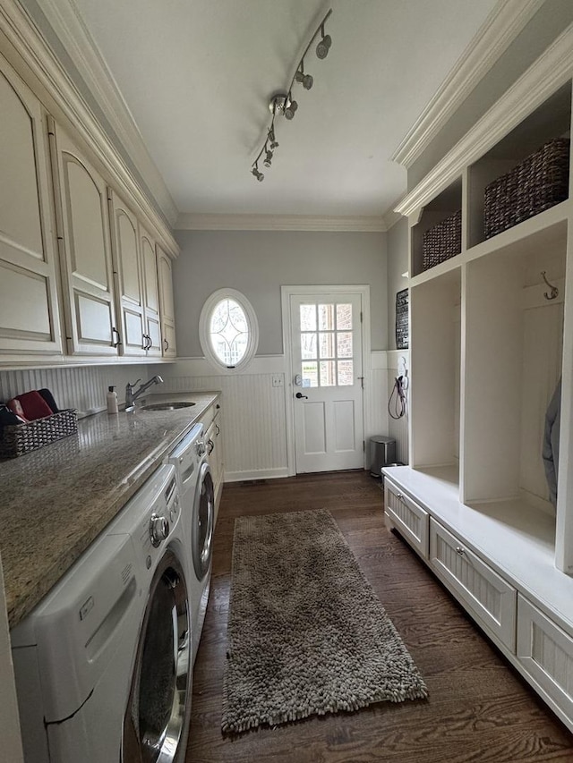 laundry room featuring washer and clothes dryer, cabinet space, a sink, a wainscoted wall, and dark wood-type flooring