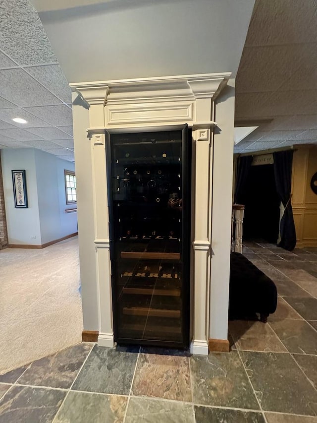 details featuring baseboards, carpet flooring, beverage cooler, and a paneled ceiling