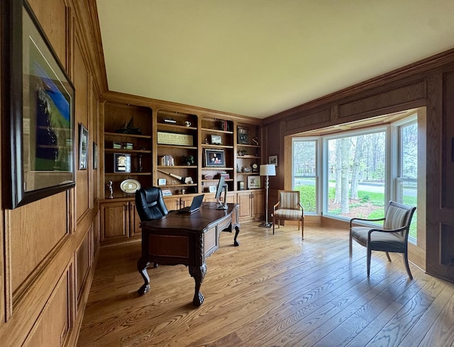 home office with crown molding, wood walls, and light wood-type flooring