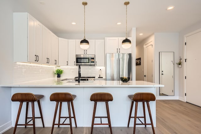 1462 W Winnemac Ave Unit 2, Chicago, IL 60640 - kitchen featuring a peninsula, wood finished floors, stainless steel appliances, decorative backsplash, and recessed lighting