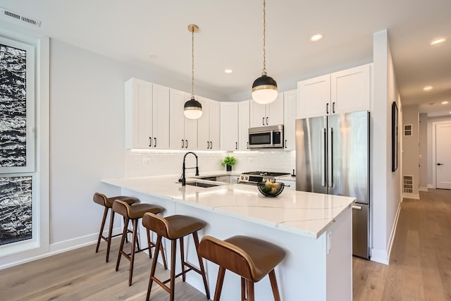 1462 W Winnemac Ave Unit 2, Chicago, IL 60640 - kitchen with a sink, stainless steel appliances, a breakfast bar area, backsplash, and baseboards
