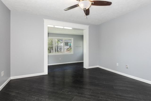 empty room featuring baseboards, a ceiling fan, and dark wood-style flooring