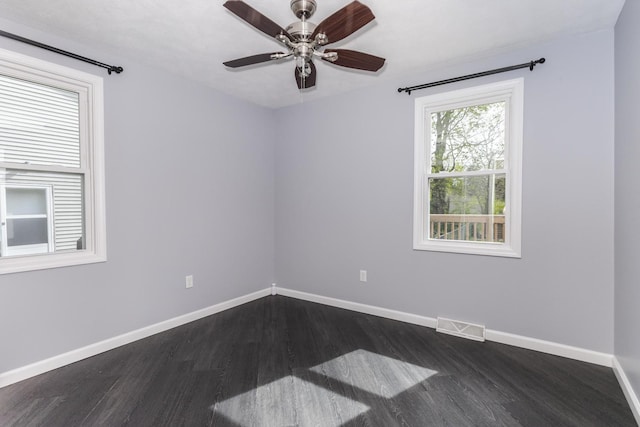 spare room featuring visible vents, a ceiling fan, baseboards, and dark wood-type flooring