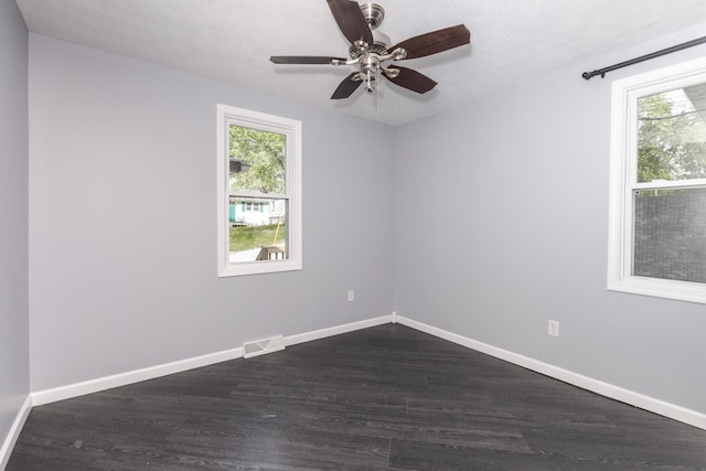 empty room with visible vents, dark wood finished floors, ceiling fan, and baseboards
