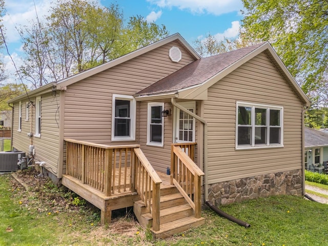 rear view of property featuring central air condition unit, a yard, a shingled roof, and a wooden deck