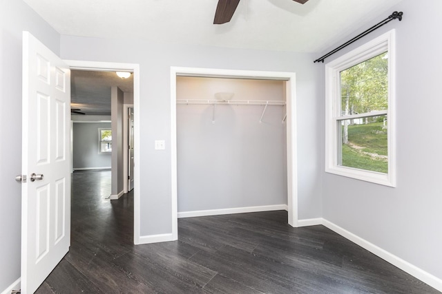 unfurnished bedroom with dark wood-type flooring, baseboards, and multiple windows