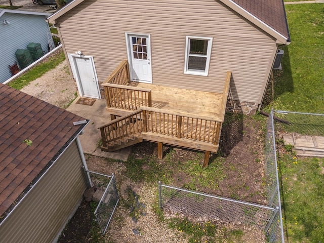rear view of property featuring fence, a wooden deck, and a shingled roof