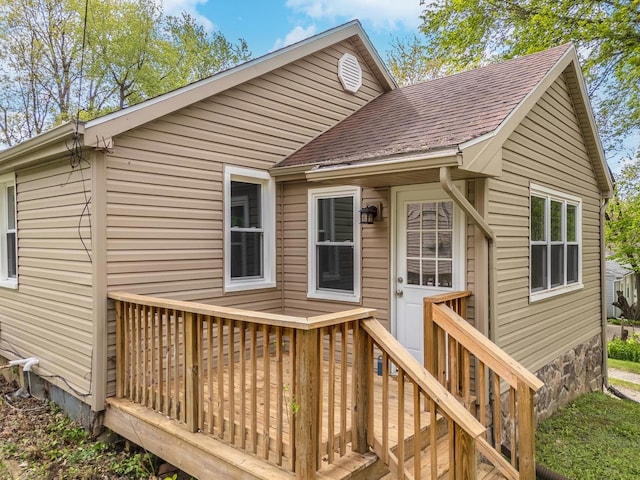 rear view of property with roof with shingles and a deck