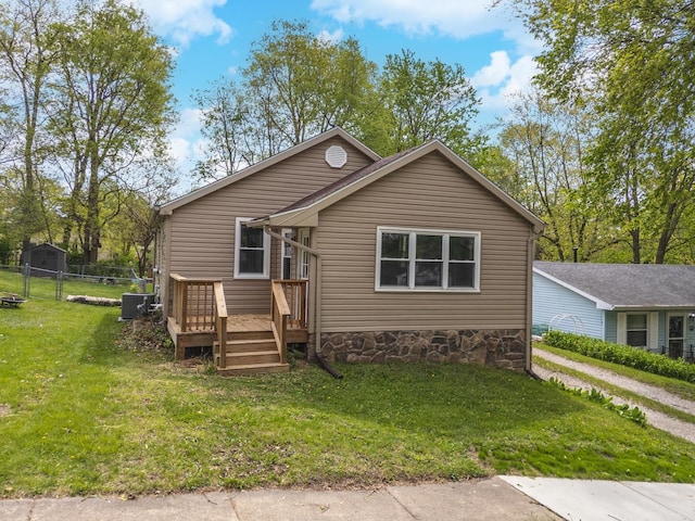 bungalow-style house featuring fence, central AC unit, a front lawn, and a deck