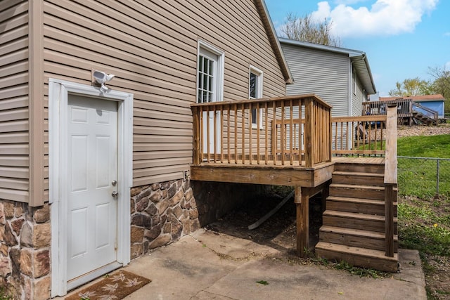 entrance to property featuring fence and a wooden deck