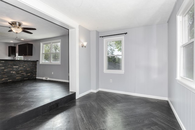 unfurnished living room featuring baseboards, ceiling fan, and a wealth of natural light