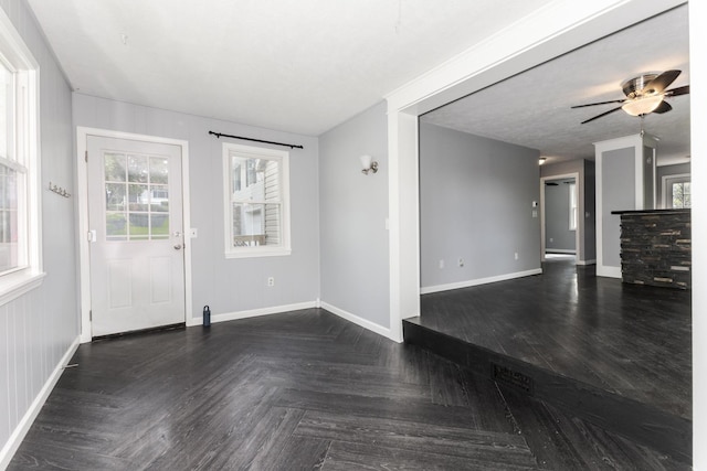 unfurnished living room featuring a ceiling fan and baseboards