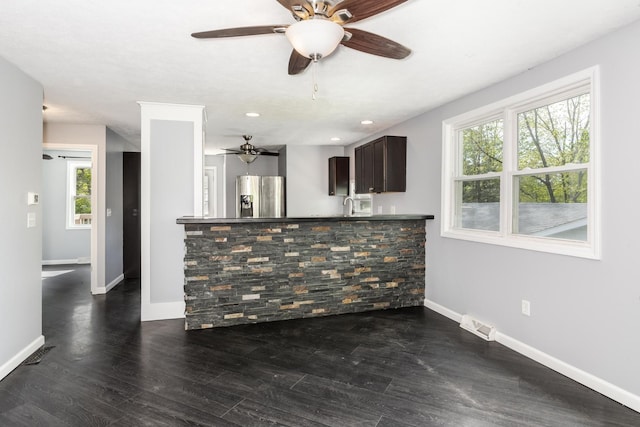 unfurnished living room featuring a healthy amount of sunlight, baseboards, ceiling fan, and visible vents