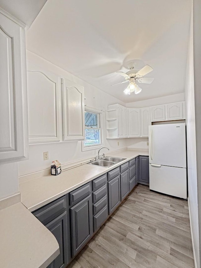 kitchen with a ceiling fan, a sink, white cabinetry, gray cabinetry, and freestanding refrigerator