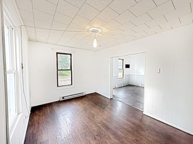 spare room with a baseboard radiator, a wealth of natural light, and dark wood-style flooring